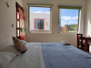 a bedroom with a large bed with two windows at Squalo's Place in Holbox Island