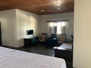 Cette chambre comprend un lit, un bureau et des chaises. dans l'établissement Casa do Vale, à Triunfo
