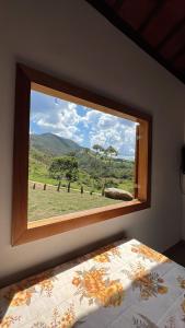 um quarto com uma janela com vista para um campo em Casa Cambuí Hospedagem Rural em Rio Prêto