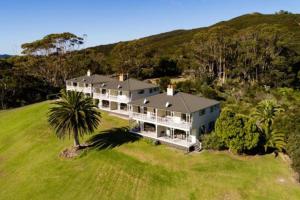 a large house on a hill with a palm tree at Carrington Estate in Tokerau Beach