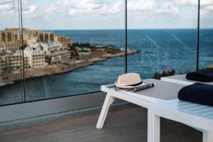 a hat sitting on a white bench in front of a window at be.HOTEL in St. Julianʼs