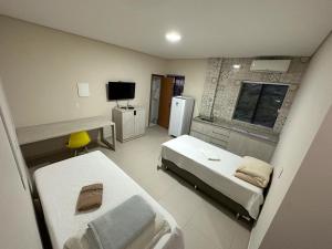 a small room with two beds and a television at Hotel Pousada Posto Carvalho in Campo Formoso