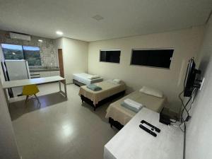a room with two beds and a desk in it at Hotel Pousada Posto Carvalho in Campo Formoso