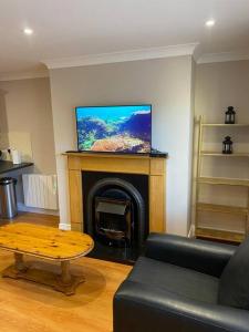 sala de estar con chimenea y TV de pantalla plana en 2 bed cosy apartment in heart of Mullingar. en Mullingar