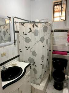 baño con aseo negro y cortina de ducha en Casa de Campo Nuestra Tierra, en Quito
