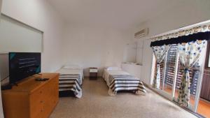 a room with two beds and a tv and a window at HABITACIONES en casa palermo con terraza y parrilla in Buenos Aires