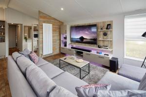 Sandy Bay Lodge في نيوبيغين-باي-ذا-سي: غرفة معيشة مع أريكة وتلفزيون بشاشة كبيرة