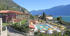 a resort with a swimming pool with umbrellas at Residence Borgo Dei Limoni - Appartamenti con Garage in Gargnano +29 photos