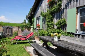 a picnic table and a red chair next to a building at Kemnater Alm in Kaufbeuren