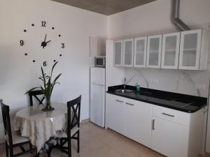uma cozinha com uma mesa e um relógio na parede em Apartamento con terraza y jardín em Las Breñas