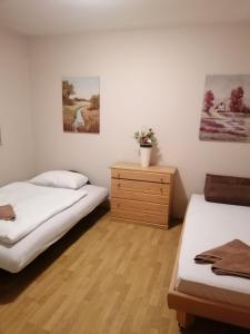 Zimmer mit 2 Betten, einer Kommode und Gemälden in der Unterkunft DenyLana Apartman in Konjic