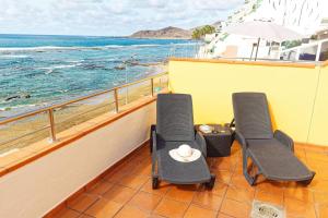 2 sillas y una mesa en un balcón con vistas al océano en Apartamentos Maype Canteras, en Las Palmas de Gran Canaria
