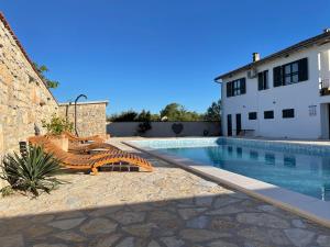 una piscina con panchina accanto a un edificio di Villa Maslina Šarić a Ðevrske