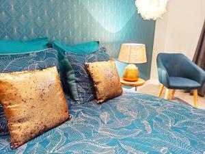 uma cama azul com almofadas e uma cadeira azul em Studio confort la plume em Pont-sur-Seine