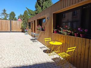 a patio with a yellow table and chairs next to a building at Studio confort la plume in Pont-sur-Seine