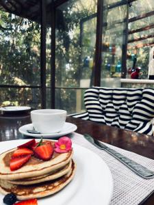 a stack of pancakes with strawberries on a table at Hotel La Casa de los Árboles Immersive Experience in Zacualpan de Amilpas