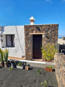 een stenen huis met een deur en wat planten bij Apartamento con terraza y jardín in Las Breñas