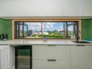 a kitchen with a window over a kitchen counter at The Little Bach at Whangapoua in Whangapoua