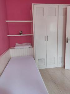 a bedroom with a white bed and pink walls at Casa Ampla e confortável in São Sebastião