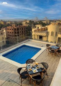un patio en la azotea con mesa, sillas y piscina en Sofia Pyramids Hotel, en El Cairo
