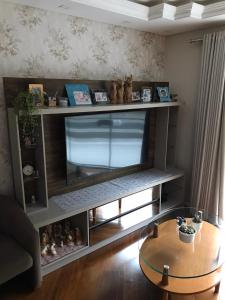 sala de estar con TV de pantalla plana en un estante en Residencial Jardim Curitiba, en Curitiba