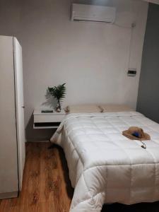 ein Schlafzimmer mit einem weißen Bett mit Hut darauf in der Unterkunft Departamento próximo a la costanera y al aeropuert in Posadas