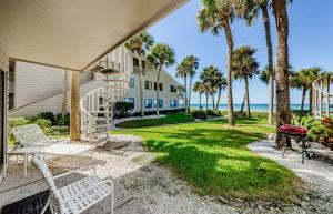 a house with a patio with palm trees and a grill at Beachfront Aldea 5 in Clearwater Beach