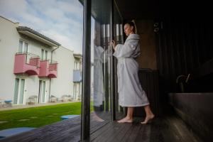 a woman in a robe looking at a window at Best Western Plus Sabaudia Hotel in Sabaudia