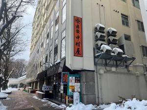 Un edificio su una strada con la neve sopra di Nakamuraya Ryokan a Sapporo