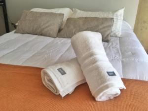 Dos toallas blancas enrolladas en una cama en Departamento Minimalista en pleno centro en San Miguel de Tucumán