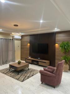 a living room with a tv and a chair and a table at Integral Consults Apartment in Abuja
