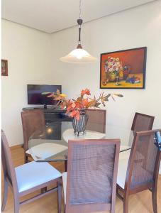 uma sala de jantar com uma mesa com um vaso de flores em Apartamento Lago Negro em Gramado