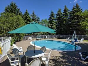 a table with an umbrella next to a swimming pool at The Century House, Ascend Hotel Collection in Latham