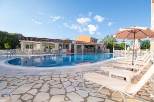 a swimming pool with chairs and an umbrella at Eriva Hotel in Acharavi
