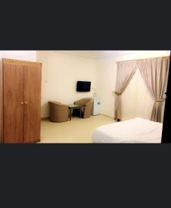 a bedroom with a bed and a cabinet and a tv at أجنحة مارينا طيبة in Al Madinah