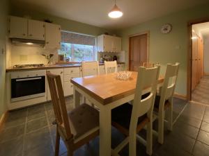 eine Küche mit einem Esstisch aus Holz und Stühlen in der Unterkunft Cottage 427 - Clifden in Clifden