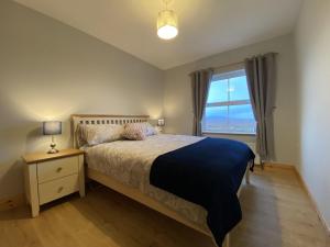ein Schlafzimmer mit einem großen Bett und einem Fenster in der Unterkunft Cottage 427 - Clifden in Clifden