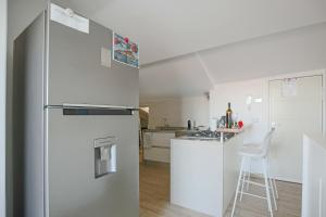 una cucina bianca con frigorifero e sgabello di Casa Valastro ad Aci Castello