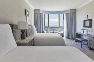 ロサンゼルスにあるビバリーウィルシャー、フォーシーズンズホテルのベッド2台とデスクが備わるホテルルームです。