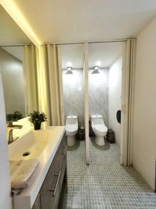 baño con 2 aseos, lavamanos y espejos en Habitación para 8 personas en Polanco Literas, en Ciudad de México