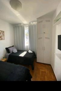 Habitación pequeña con 2 camas y TV. en Ap da Lú en Teresópolis