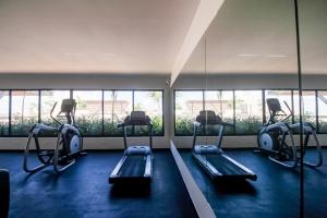un gimnasio con varias cintas de correr en una habitación con ventanas en Syrena 503 en Playa del Carmen