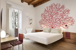 una camera da letto con un letto bianco e un grande albero appeso al muro di Casa Clat a Cagliari