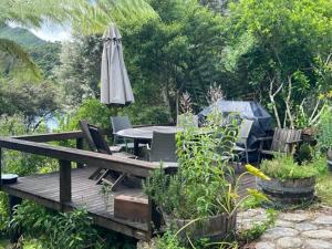 eine Holzterrasse mit Tisch und Sonnenschirm in der Unterkunft Waterfall Bay in Broughton Bay