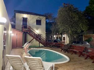 a swimming pool in a yard with chairs and a building at Pousada Encantos da Amazônia in Alter do Chao