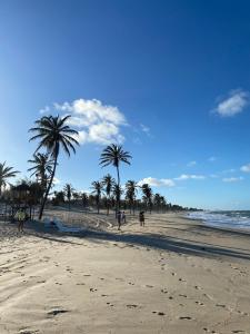 a beach with palm trees and people on the sand at Apartamento Cumbuco, c2 307 in Caucaia