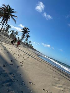 two people walking on a beach with palm trees at Apartamento Cumbuco, c2 307 in Caucaia