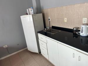 a kitchen with a white refrigerator and a sink at Cerro Arco Apart Hotel in El Challao