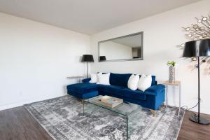 sala de estar con sofá azul y espejo en Prime Location 1-Bedroom with Balcony and Pool en Los Ángeles