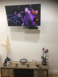 un televisor colgando de una pared con una orquesta en él en Cosy & Tendance Spa, en Poitiers